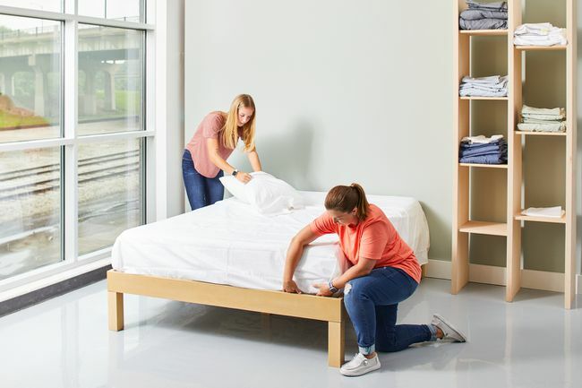 dvi moterys kloja lovą baltais paklodėmis